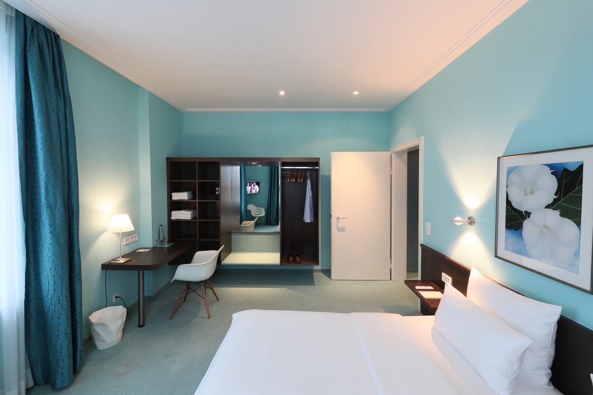 Blick auf ein hellbeleuchtetes Hotelzimmer mit einem Doppelbett