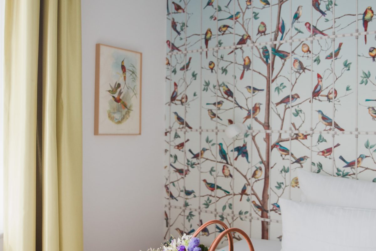 View of colorful bouquet of flowers in front of a colorful wallpaper and yellow curtains