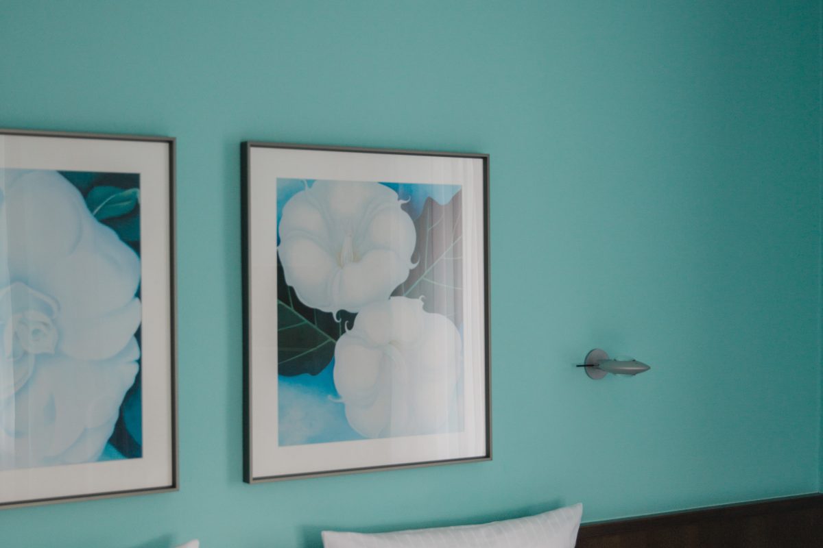 Blick auf eine blaue Tapete mit zwei Blumengemälden 