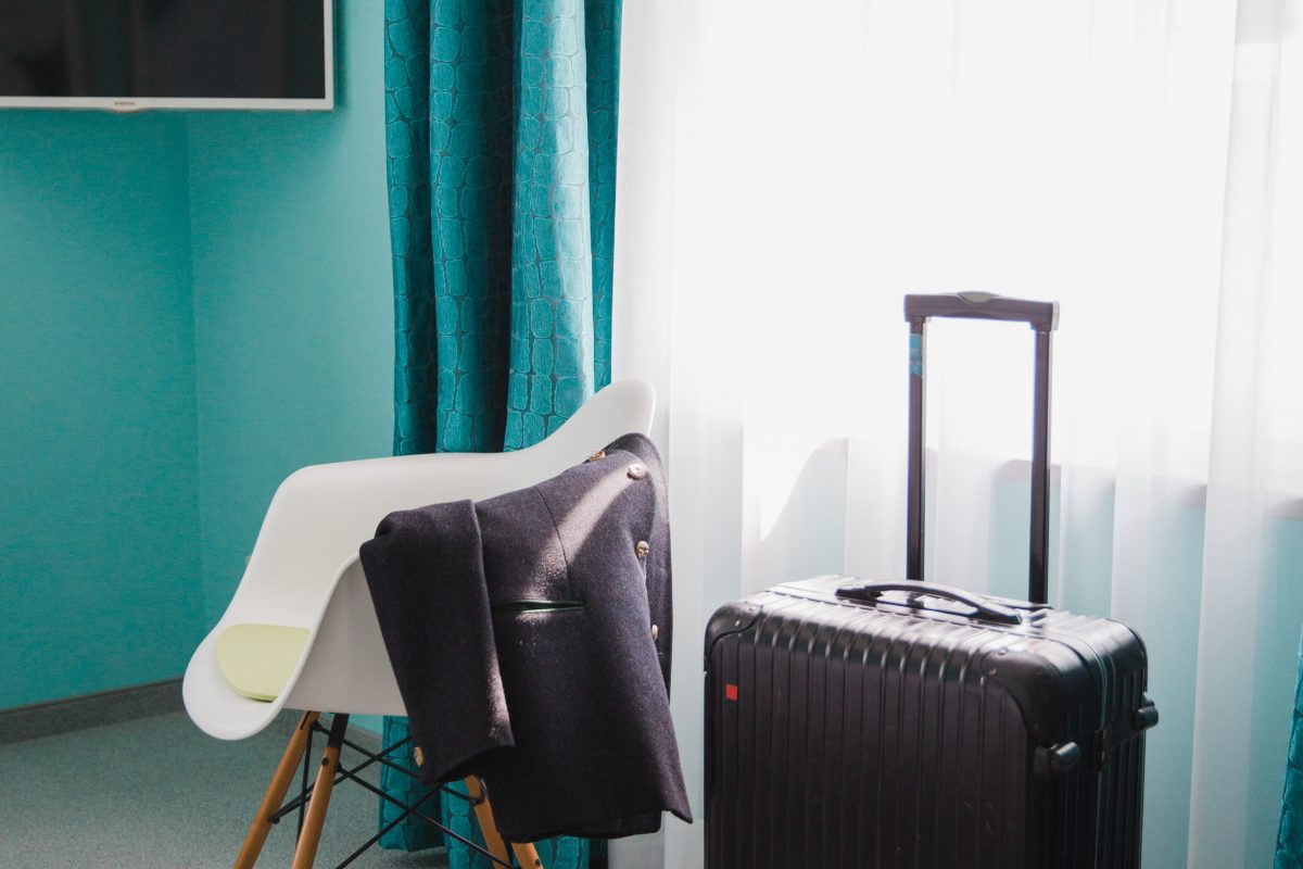 View of a suitcase in front of turquoise ceiling and turquoise curtains 