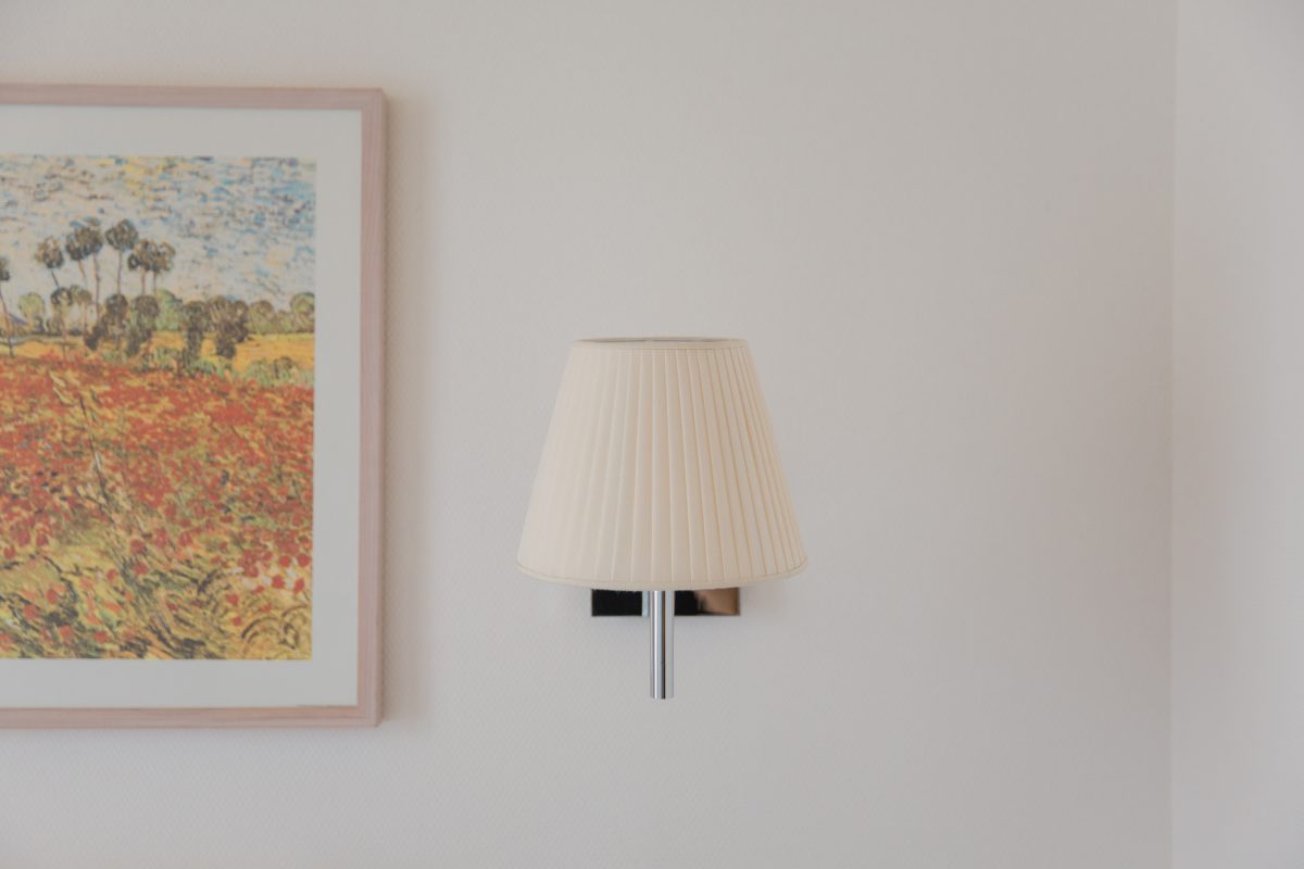 Blick auf eine stilvolle Lampe an der Wand neben einem bunten Gemälde