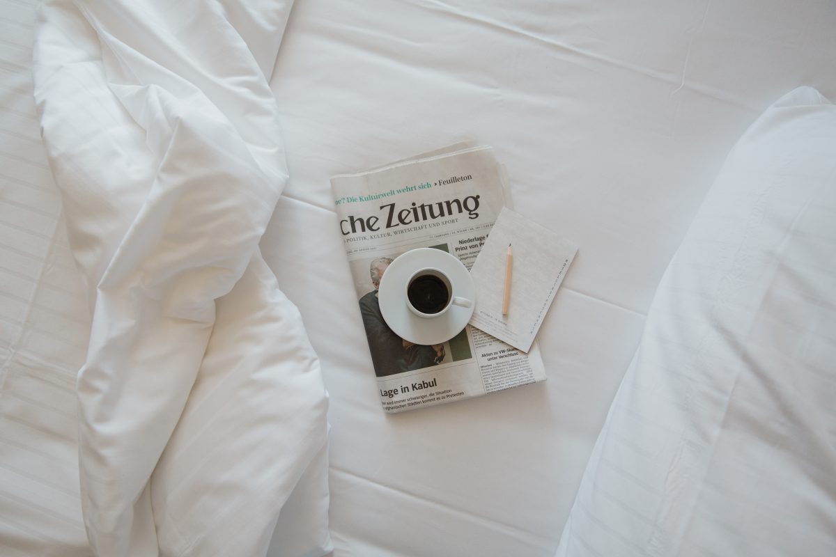 View on a news paper and coffee on a hotel bed 