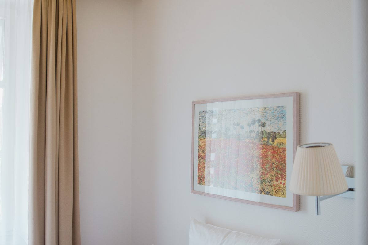 Blick auf ein Einzelbett vor einem bunten Gemälde