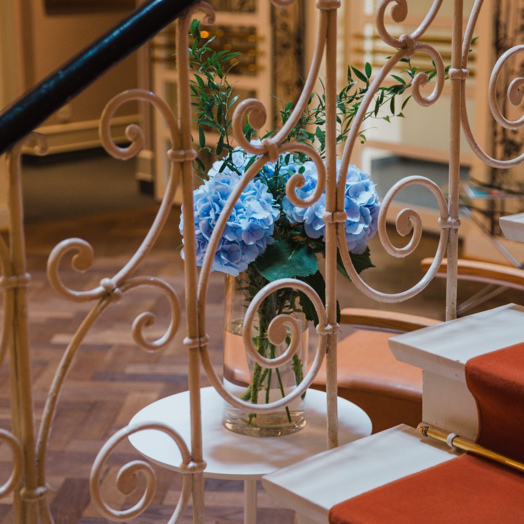 Blick auf ein kunstvolles Treppengeländer und eine Blumenvase