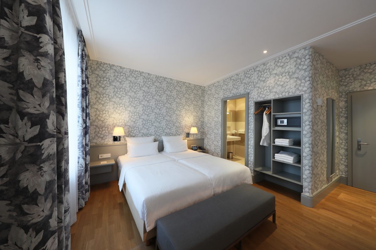 Double bed in spacious suite with flowered wallpaper